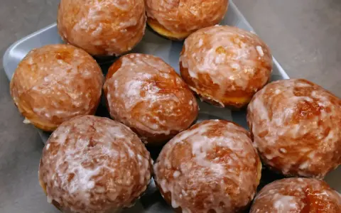 Puszyste pączki z piekarnika, oblane lukrem, kuszą swoim wyglądem. Idealne na tłusty czwartek lub jako słodka przekąska.