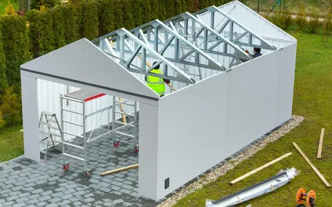 Budowa garażu w toku. Pracownicy montują konstrukcję dachu. Może to być kara za postawienie blaszaka bez zgłoszenia, jeśli nielegalnie.