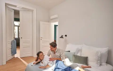 Pareja relajada en la cama, disfrutando de un ambiente fresco gracias al aire acondicionado, ideal para un buen sleep.