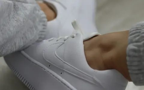 Białe sneakersy z szarym swetrem. Dowiedz się, jak zabezpieczyć białe buty, by długo wyglądały jak nowe.