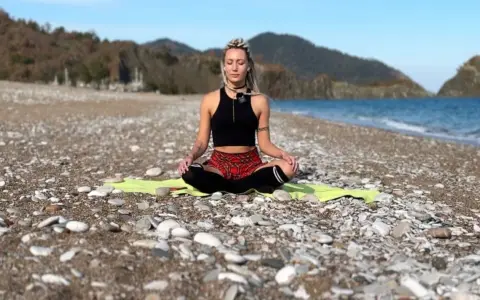 Frau in Meditation am Strand, tiefe Konzentration auf die Wellen.