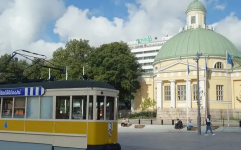 Żółty tramwaj na tle katedry i nowoczesnego budynku. Turku atrakcje to nie tylko zabytki, ale i miejska komunikacja.
