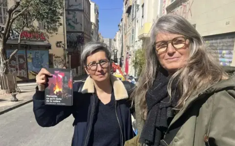 Deux femmes, l'une tenant un livre, dans une rue de Marseille. Le visage de madone de l'une d'elles est encadré par des lunettes.
