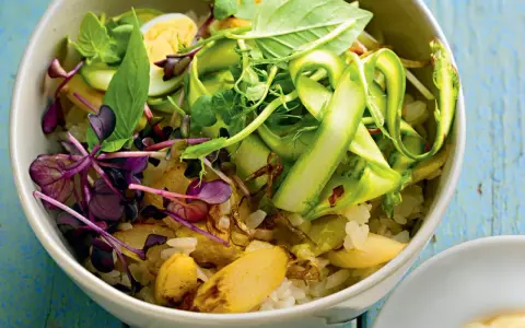 Eine bunte Spargel Bowl mit Reis, Ei, Sprossen und frischen Kräutern, appetitlich angerichtet.