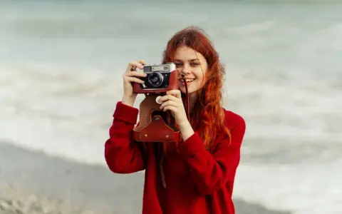 Ruda dziewczyna z aparatem, jak znani fotografowie, uwiecznia piękno morza.