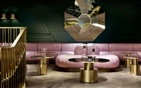 Salon chic avec canapé rose poudré, tables basses dorées et miroir géométrique. Une ambiance **déco belle époque** moderne.