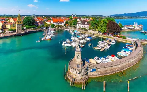Malowniczy port nad Jeziorem Bodenskim z licznymi jachtami, latarnią morską i zabytkową zabudową miasta.