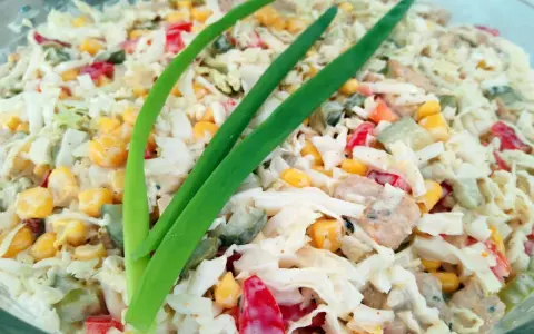Pyszna sałatka gyros mieszana z kurczakiem, kukurydzą, papryką i ogórkiem, udekorowana szczypiorkiem.