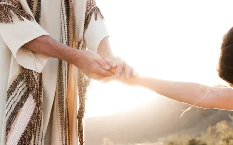 A person in a robe holds another's hand, symbolizing how to surrender to God through trust and guidance.