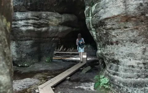 Spacerka po skalnych labiryntach Gór Stołowych. Drewniany pomost prowadzi przez mokradła między potężnymi skałami.
