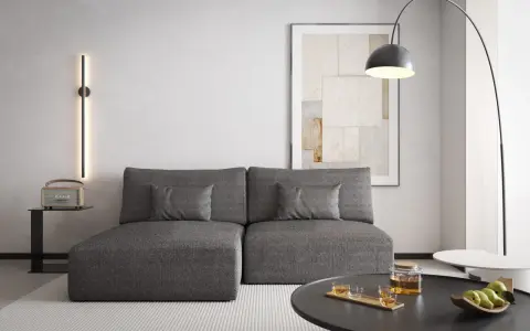Nowoczesny salon z szarą kanapą, na ścianie pionowa lampa emitująca zielone światło. Czy zielony pasuje do szarego? Tak, tworzy przytulną atmosferę.