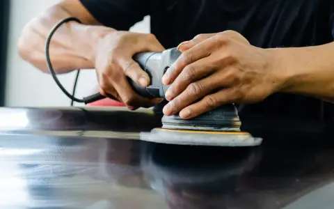 Ręce trzymają polerkę, która wykonuje polerowanie aluminium. Powierzchnia staje się lśniąca.