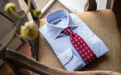 Camicia bianca a righe azzurre con cravatta bordeaux a fantasia floreale, pronta per un abito blu.