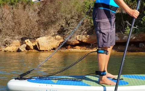 Person befestigt sup leash an Hüfte und Bein für sicheren Stand auf dem Board.