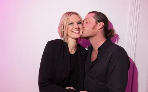 Sanna Nielsen ler när en man med hästsvans ger henne en puss på kinden.