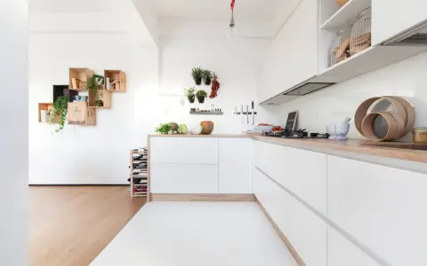 Progetto cucina angolare piccola: mobili bianchi minimalisti, piano in legno, mensole a muro con piante e vasi.