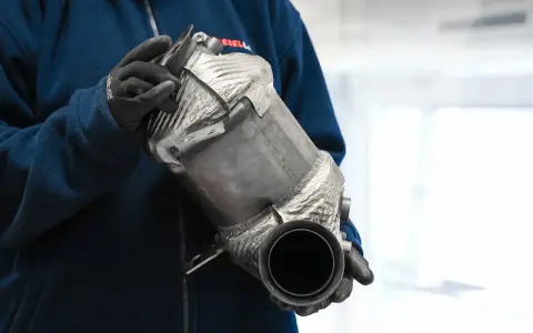 Osoba w rękawiczkach trzyma filtr cząstek stałych DPF.