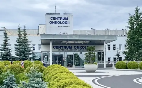 Budynek Centrum Onkologii w Bydgoszczy z zielenią przed wejściem.