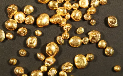 Grains d'or brut, certains ressemblant à des pépites, d'une pureté qui pourrait être du poinçon or 14 carats.