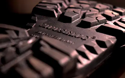 Detalle de la suela de caucho de una bota, con un patrón de tacos pronunciados. La inscripción "SLIP RESISTANT" confirma que la suela de caucho no resbala.