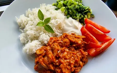 En smakrik kebabgryta med ris, serverad med fräscha tomater och en klick vit sås. En perfekt middag!