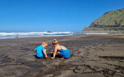 Dzieci budują zamki z piasku na czarnej plaży. Teneryfa atrakcje dla dzieci to raj dla małych odkrywców.