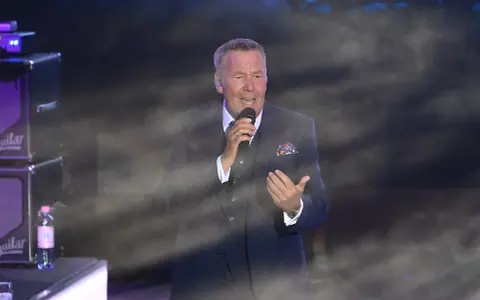 Roland Kaiser singt in Berlin. Der Künstler trägt einen dunklen Anzug und hält ein Mikrofon.