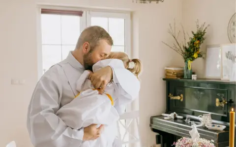 Ojciec obejmuje córkę w bieli, przygotowując ją do tego, co dziecko musi umieć do pierwszej komunii.