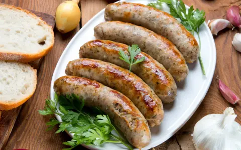 Pięć soczystych białych kiełbasek z piekarnika, podanych z chlebem, cebulą i czosnkiem.