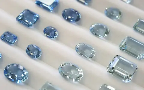 Collezione di acquamarine con taglio smeraldo e altre forme, che brillano su un morbido sfondo bianco.