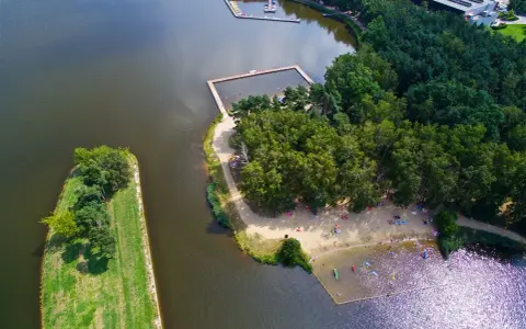 Widok z lotu ptaka na jezioro z kąpieliskiem, plażą i lasem.