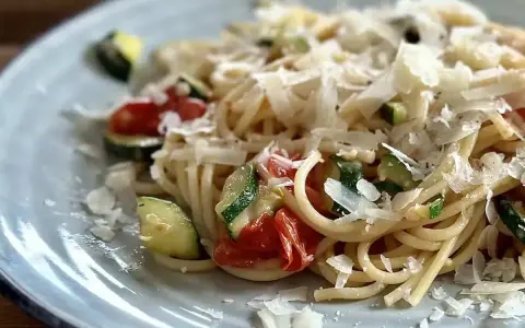 Pyszny makaron z pomidorkami koktajlowymi, cukinią i parmezanem. Idealny letni posiłek.