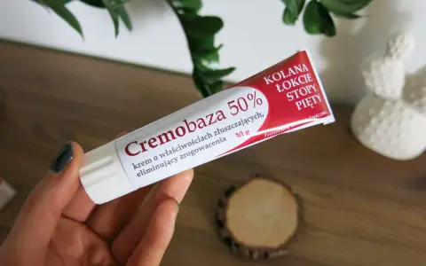 Dłoń trzyma tubkę kremu Cremobaza 50%, który pomaga na zrogowacenia. Brak informacji o skutkach ubocznych.