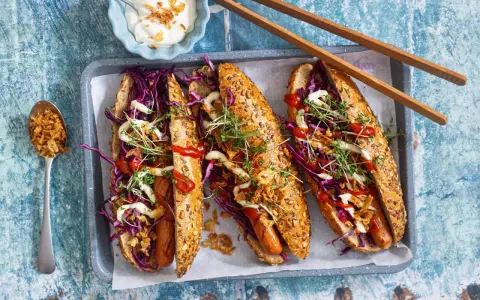 Drei leckere Hotdogs mit Rotkohl, Kresse und Röstzwiebeln – perfekt für vegetarisches Grillen!