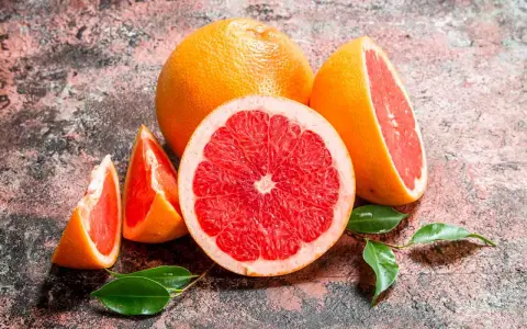 Saftige Grapefruits, frisch aufgeschnitten und als Spalten, mit grünen Blättern. Grapefruit gesund und lecker.