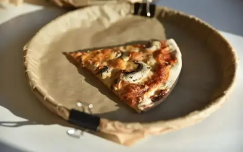 Kawałek pysznej pizzy capricciosa z pieczarkami i serem, idealna na szybki lunch.