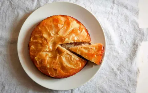 Tarta de manzana esponjosa, dorada y jugosa, con una porción recién cortada lista para disfrutar.