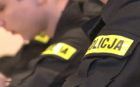 Zbliżenie na rękawy mundurów policyjnych z żółtymi naszywkami "POLICJA".