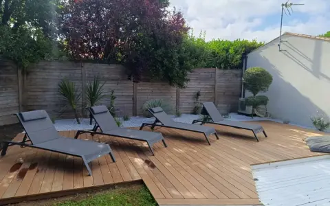 Aménagement terrasse en bois avec chaises longues invitant à la détente. Un espace extérieur parfait pour profiter du soleil.