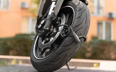 Zabezpieczenie motocykla przed kradzieżą: gruby, czarny łańcuch oplatający oponę i tarczę hamulcową.