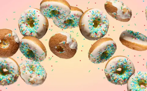 Bunte Donuts mit weißer Glasur und Streuseln schweben im Bild. Ein köstliches Rezept für selbstgemachte Donuts.