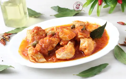 Un invitante pollo alla pizzaiola, con pezzi succulenti immersi in una ricca salsa di pomodoro, capperi e profumate foglie di alloro.