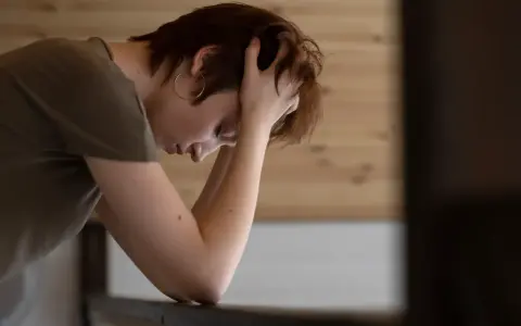 En person med händerna i håret, ser nedåt. Kanske en bild som visar hur man kan tänka kring hur minskar man stress.