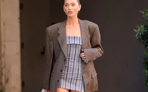 Frau in kariertem Blazer und gestreiftem Kleid. Der Blazer ist leicht zerknittert, als ob sie ihn gerade aus der Wäsche genommen hätte.