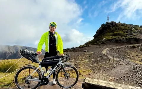 Glücklicher Radfahrer mit seinem Rennrad auf Madeira, bereit für eine Bergfahrt.
