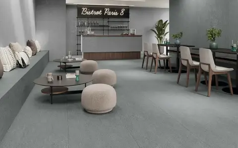 Modern café con suelo de baldosas grises, asientos de banco, mesas bajas y sillas. Ideal para aprender como colocar baldosas en el suelo.