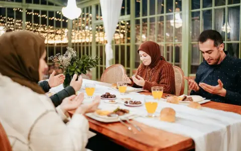 Familie betet vor dem Iftar. Sie fragen sich, was sagt man wenn man fasten will, bevor sie essen.