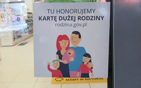 Plakat informujący o honorowaniu Karty Dużej Rodziny z rysunkiem rodziny.