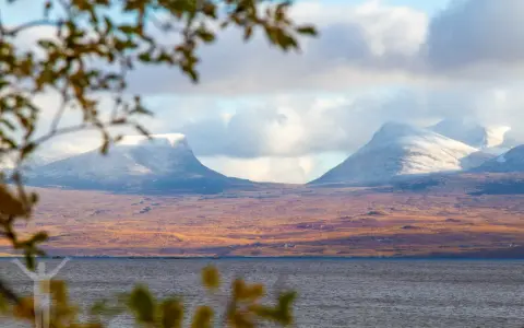 Vacker vy över Lapporten i Abisko, Sverige. Snöklädda berg reser sig över en höstfärgad tundra vid en sjö.