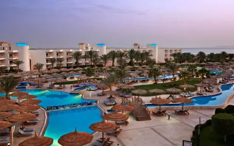 Luksusowy long beach resort Hurghada z basenami, palmami i widokiem na morze.